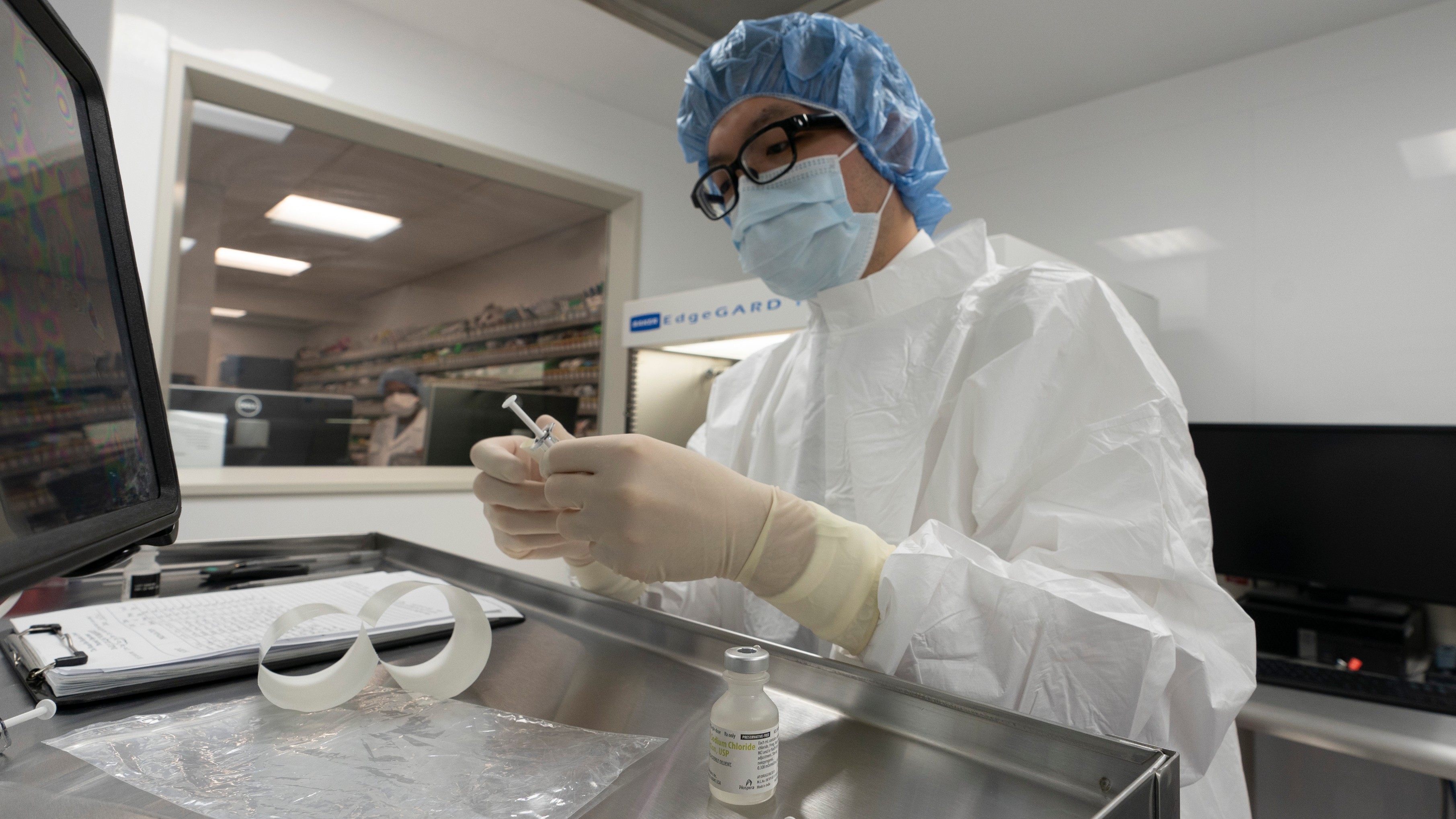 A pharmacist labels syringes in a clean room where doses of COVID-19 vaccines will be handled on Wednesday at Mount Sinai Queens hospital in New York. (AP Photo/Mark Lennihan)